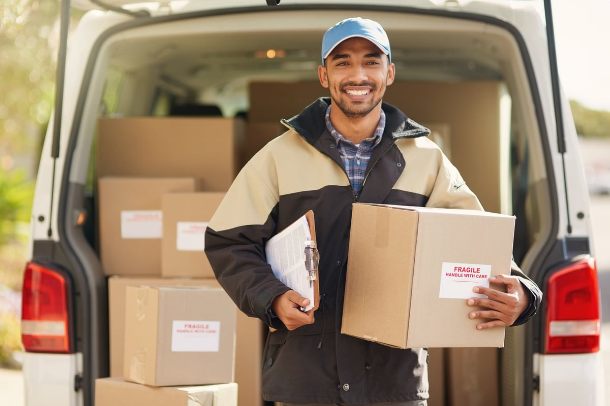 Smiling delivery driver standing in front of his van holding a package